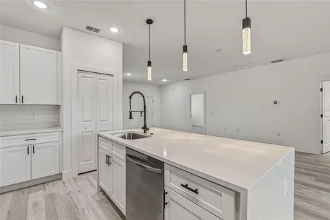 a kitchen with a sink a stove a refrigerator and white cabinets with wooden floor