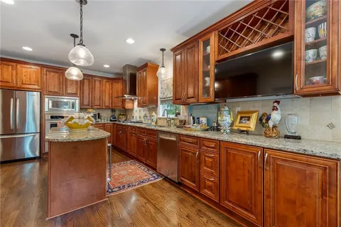 a kitchen with granite countertop wooden cabinets a sink a stove and stainless steel appliances