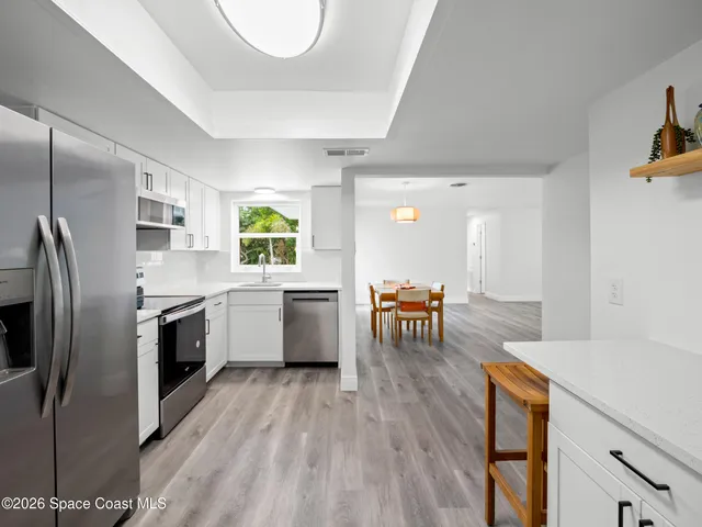 a kitchen with stainless steel appliances granite countertop a refrigerator a stove and a wooden floors