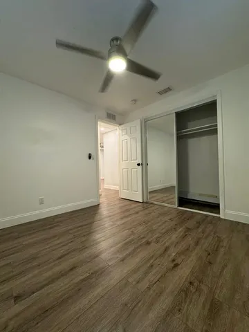 an empty room with wooden floor & closet area