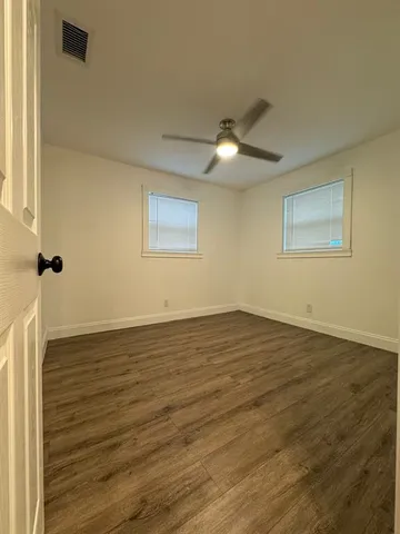 a view of an empty room with wooden floor and a window