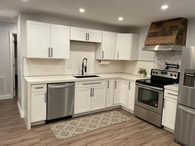 a kitchen with cabinets stainless steel appliances and wooden floor