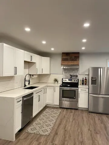 a kitchen with stainless steel appliances granite countertop a stove top oven a sink and a refrigerator