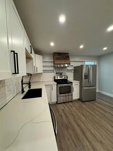 a kitchen with stainless steel appliances granite countertop a sink a stove and a refrigerator