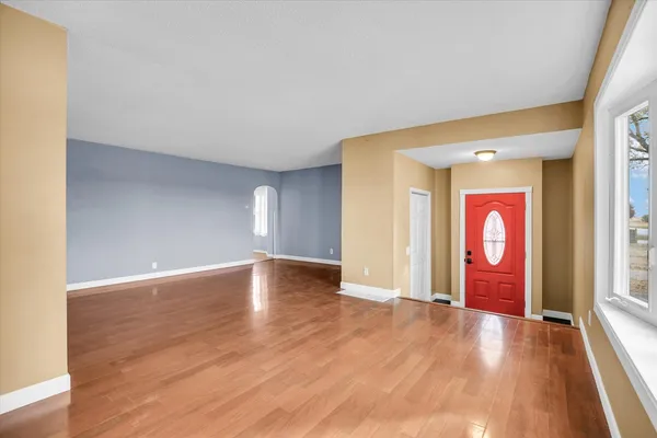 a view of an empty room with window and wooden floor