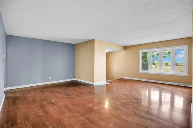 an empty room with wooden floor and window