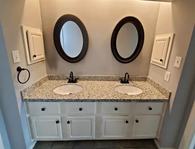 a bathroom with a granite countertop double vanity and a mirror