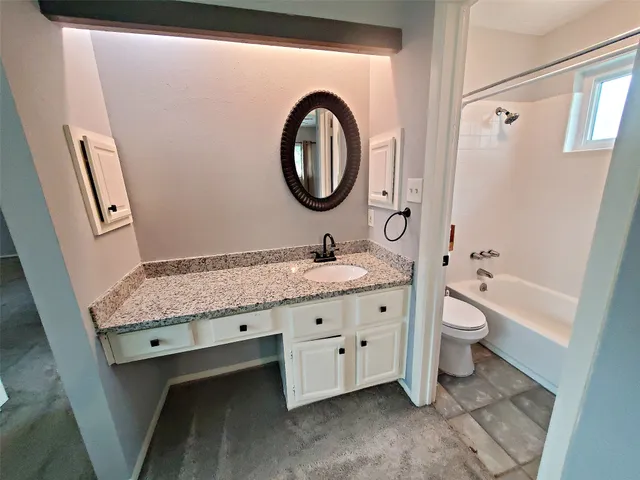 a bathroom with a granite countertop toilet a sink and a mirror