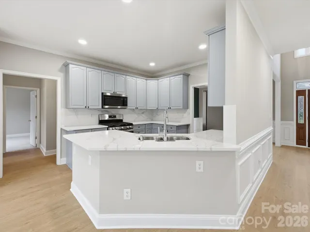a kitchen with kitchen island granite countertop a sink and a stove top oven with wooden floor
