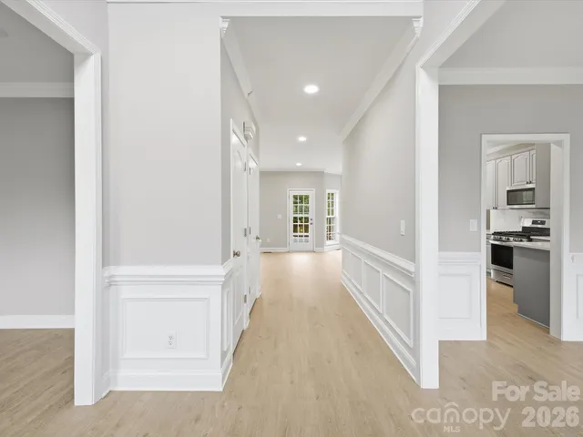 a view of a hallway with wooden floor kitchen view and a living room