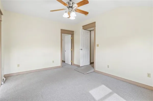 an empty room with a chandelier fan and a ceiling fan