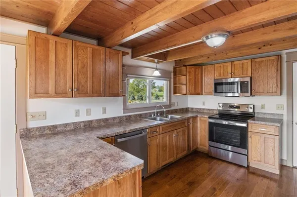 a kitchen with stainless steel appliances granite countertop wooden cabinets a sink and dishwasher a oven with wooden floors