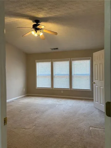 an empty room with windows and fan