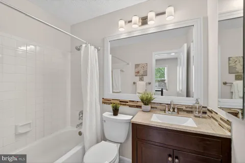 a bathroom with a sink vanity mirror toilet and bathtub