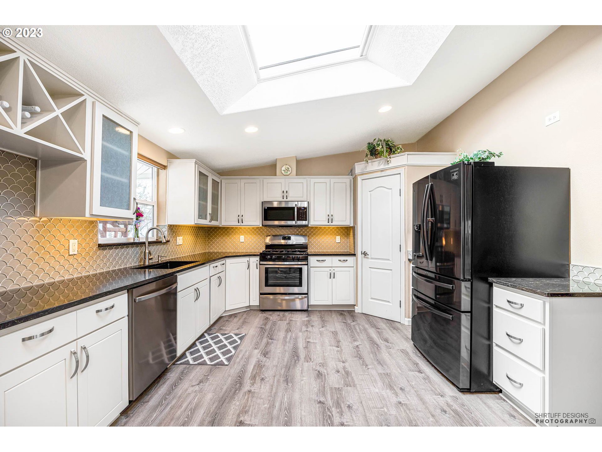 2458 Blue Boy Lane Eugene, OR 97404 - Photo 12 of 28 a kitchen with stainless steel appliances kitchen island granite countertop a refrigerator oven a sink dishwasher and white cabinets with wooden floor