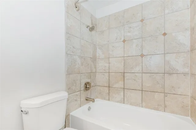 a bathroom with a white bathtub a sink a toilet and a shower