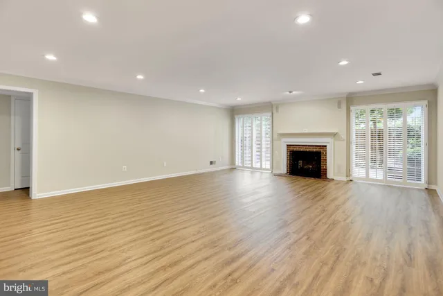 an empty room with wooden floor and a fireplace
