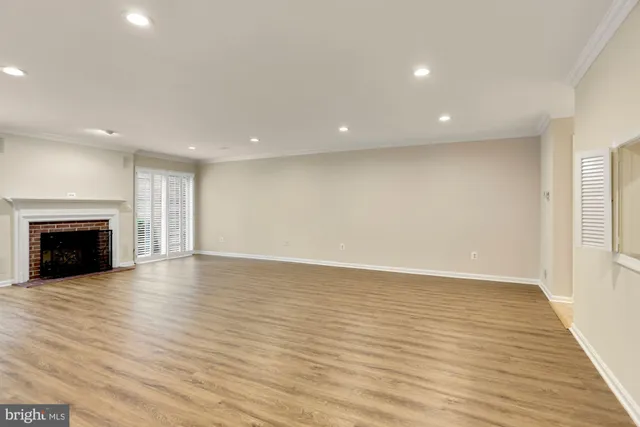 an empty room with wooden floor and fireplace