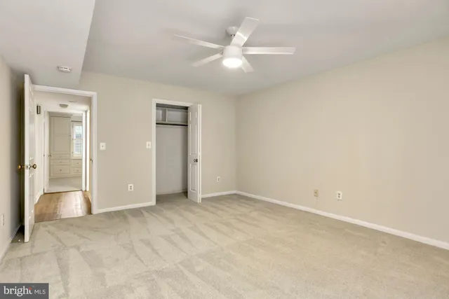 an empty room with closet and a ceiling fan
