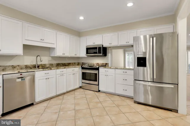 a kitchen with white cabinets stainless steel appliances and a window