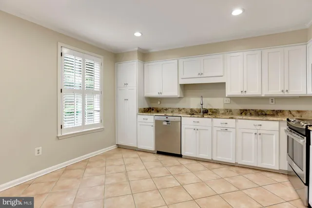 a kitchen with granite countertop white cabinets stainless steel appliances a sink and a window