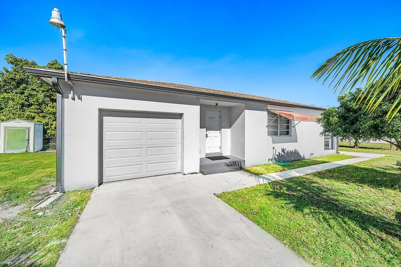 3527 Kirk Road Lake Worth, FL 33461 - Photo 8 of 25 a front view of a house with a yard and garage