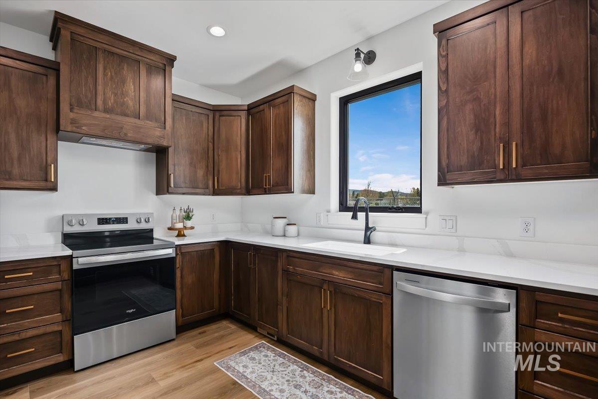107 3rd Street West Declo, ID 83323 - Photo 11 of 25 Kitchen featuring dark wood cabinetry, white countertops, stainless steel appliances, a built-in oven, and a single-basin sink with a matte black faucet