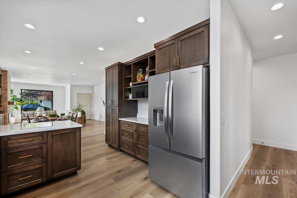 107 3rd Street West Declo, ID 83323 - Photo 14 of 25 Kitchen featuring wood-finish flooring, dark wood cabinetry with brass hardware, a stainless steel refrigerator, white countertops, and recessed lighting