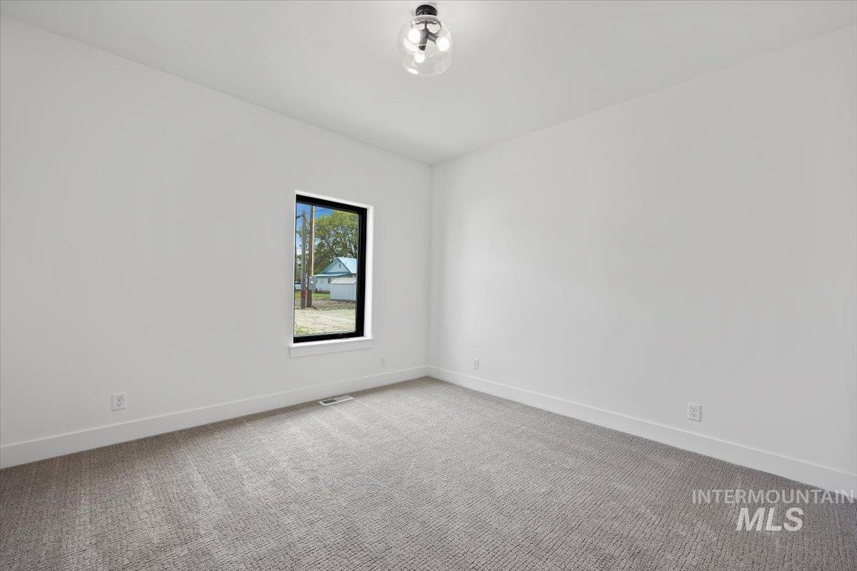 107 3rd Street West Declo, ID 83323 - Photo 19 of 25 Carpeted room featuring a single window with black trim, white walls, white baseboards, and a contemporary ceiling light fixture