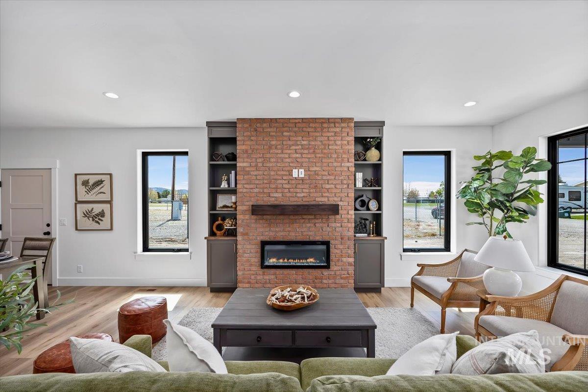 107 3rd Street West Declo, ID 83323 - Photo 2 of 25 Living area featuring a brick-clad fireplace with an integrated electric insert and wood mantel, flanked by built-in cabinetry and shelving
