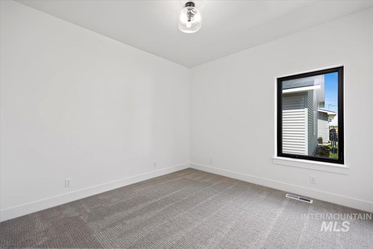 107 3rd Street West Declo, ID 83323 - Photo 21 of 25 Bright room featuring neutral wall paint, a single window with a black frame, and patterned grey carpeting