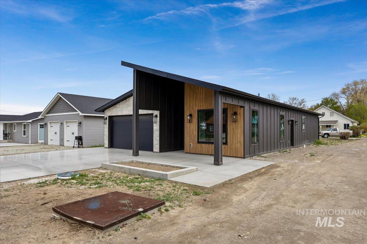107 3rd Street West Declo, ID 83323 - Photo 25 of 25 Contemporary architectural style featuring a dramatic sloped roofline, black vertical siding, wood-finish accent panels, and a stone facade