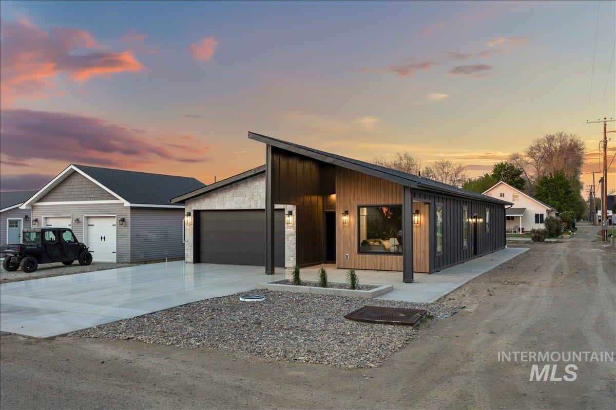 107 3rd Street West Declo, ID 83323 - Photo 26 of 29 Modern architectural design featuring vertical siding, stone accents, a single-car garage, concrete driveway, and minimalist landscaping