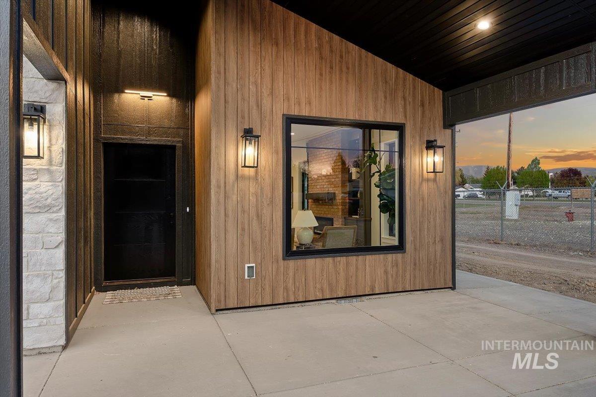 107 3rd Street West Declo, ID 83323 - Photo 27 of 29 Covered entry featuring a black paneled door with overhead lighting, stone siding, and wood-finish paneling