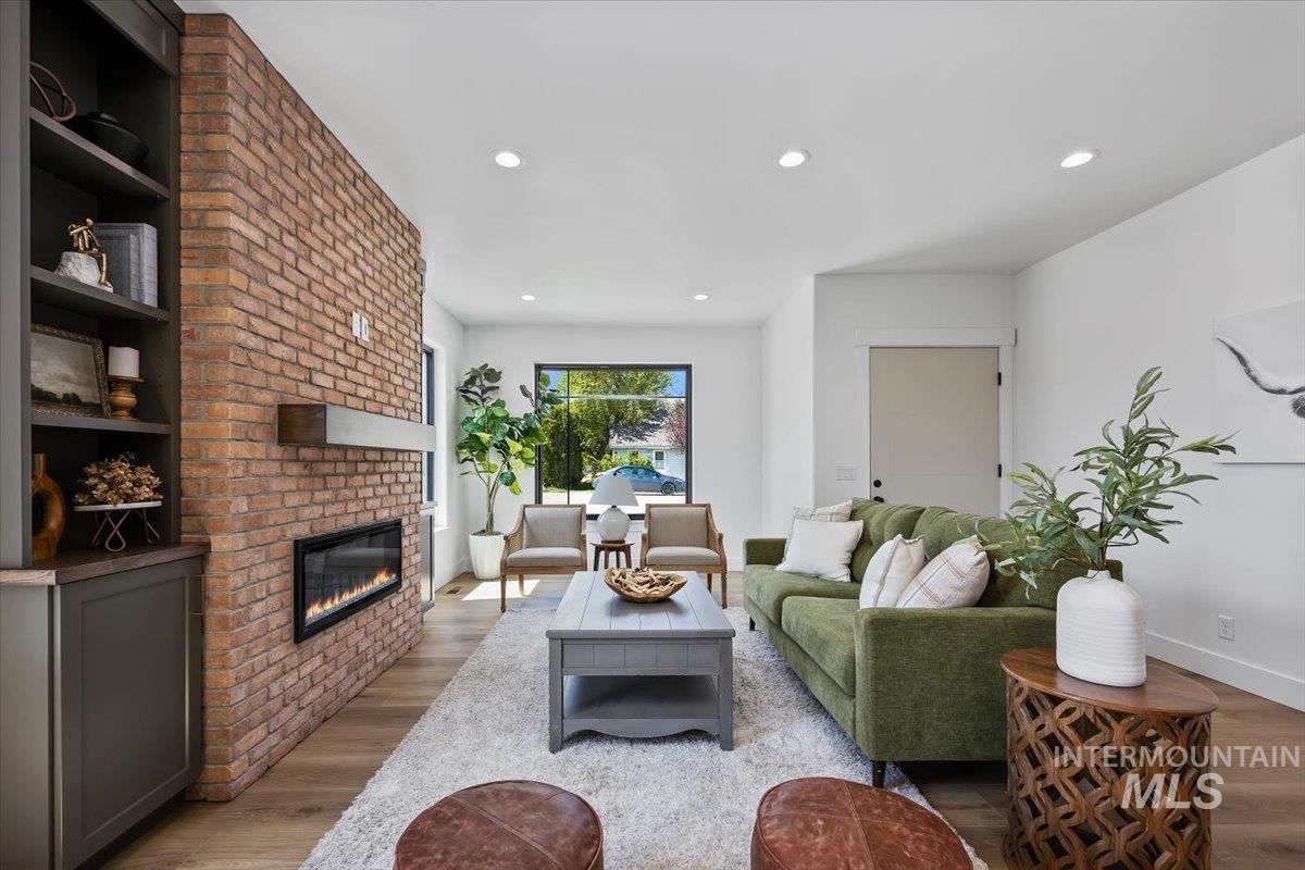 107 3rd Street West Declo, ID 83323 - Photo 5 of 25 Spacious living area featuring a full brick accent wall, linear electric fireplace, built-in shelving, wood-finish flooring, and recessed lighting