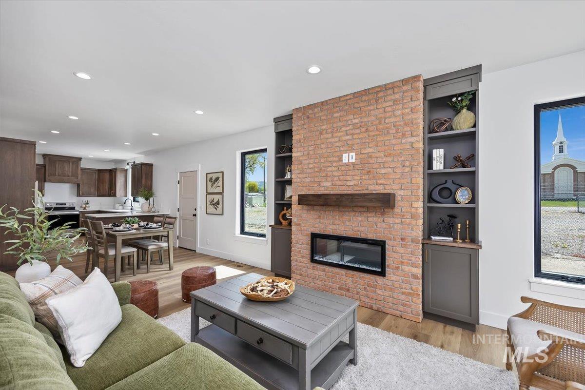 107 3rd Street West Declo, ID 83323 - Photo 7 of 25 Open-concept living space featuring a brick-clad fireplace with an electric insert, a wood mantel, and built-in shelving