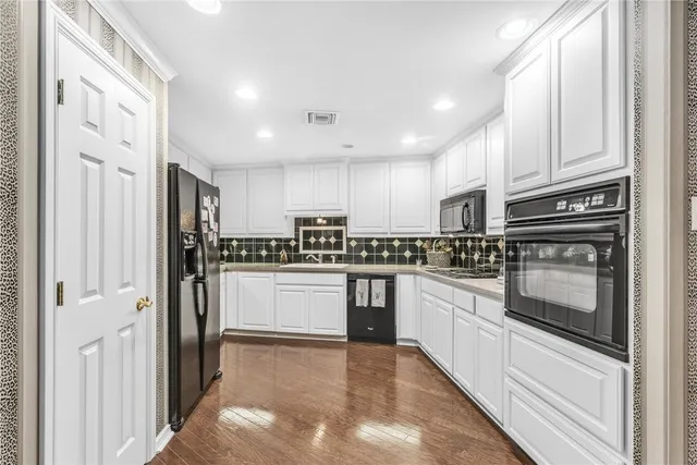 a kitchen with stainless steel appliances granite countertop white cabinets and a stove