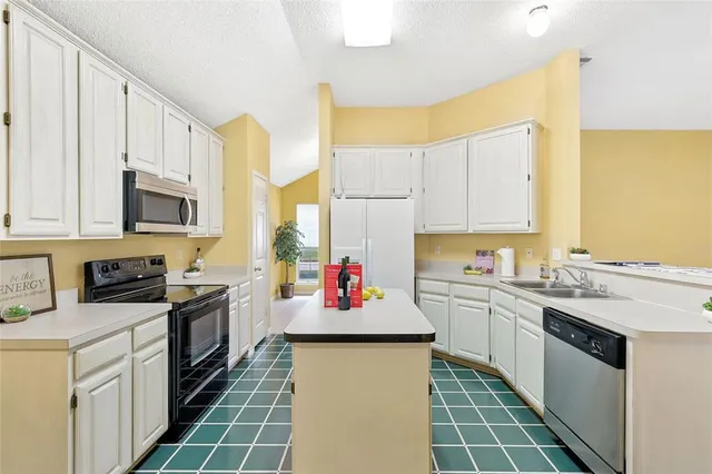 a kitchen with stainless steel appliances granite countertop a sink stove refrigerator and white cabinets