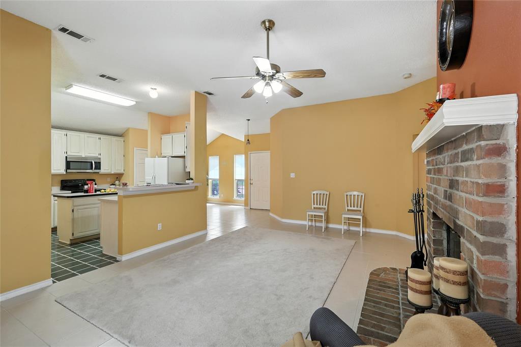 4609 Hunters Ridge Drive Sachse, TX 75048 - Photo 7 of 38 a living room with furniture a fireplace kitchen view and a chandelier