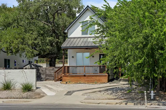 a view of a house with a yard plants and large tree