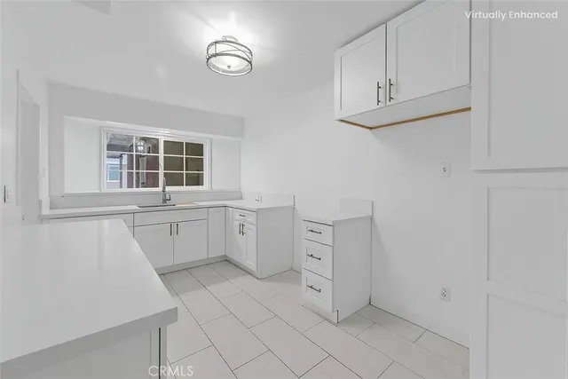 a kitchen with white cabinets and window