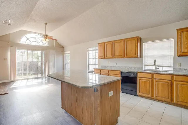 a kitchen with granite countertop a sink dishwasher stove and cabinets with wooden floor