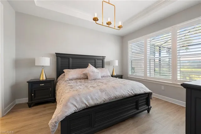 a large bed sitting in a bedroom next to a window and a chandelier