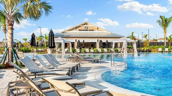 a view of a swimming pool with lawn chairs and plants