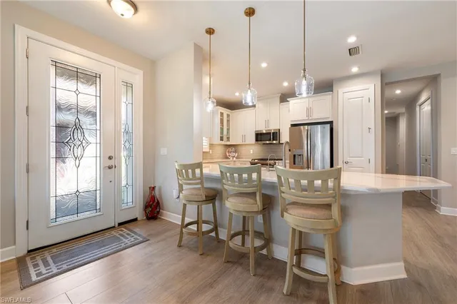 a kitchen with kitchen island stainless steel appliances a dining table chairs sink and cabinets
