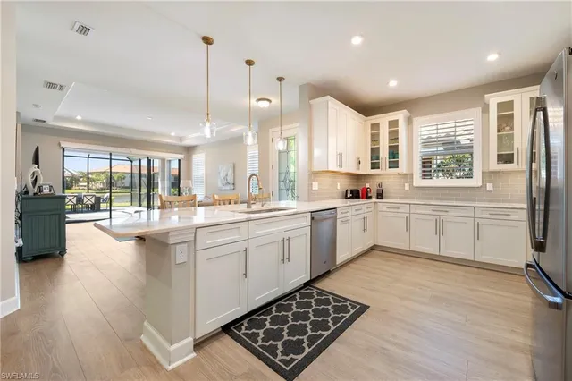 a kitchen with stainless steel appliances kitchen island granite countertop a stove a sink and white cabinets with wooden floor