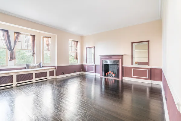 a view of a livingroom with furniture wooden floor fireplace and windows