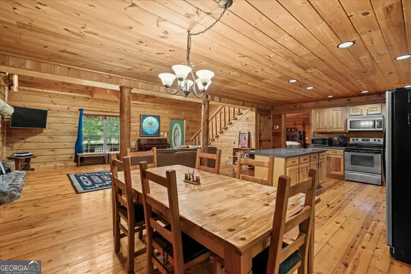 a dining room with wooden floor a chandelier a wooden table and chairs