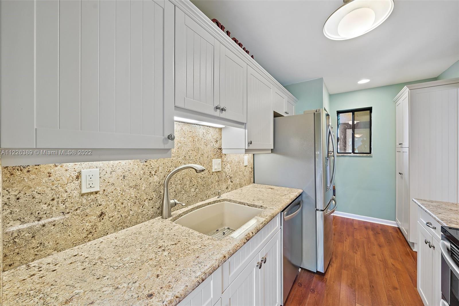 5335 Southeast Miles Grant Road, Unit 107 Stuart, FL 34997 - Photo 11 of 44 a kitchen with granite countertop a sink a stove and refrigerator