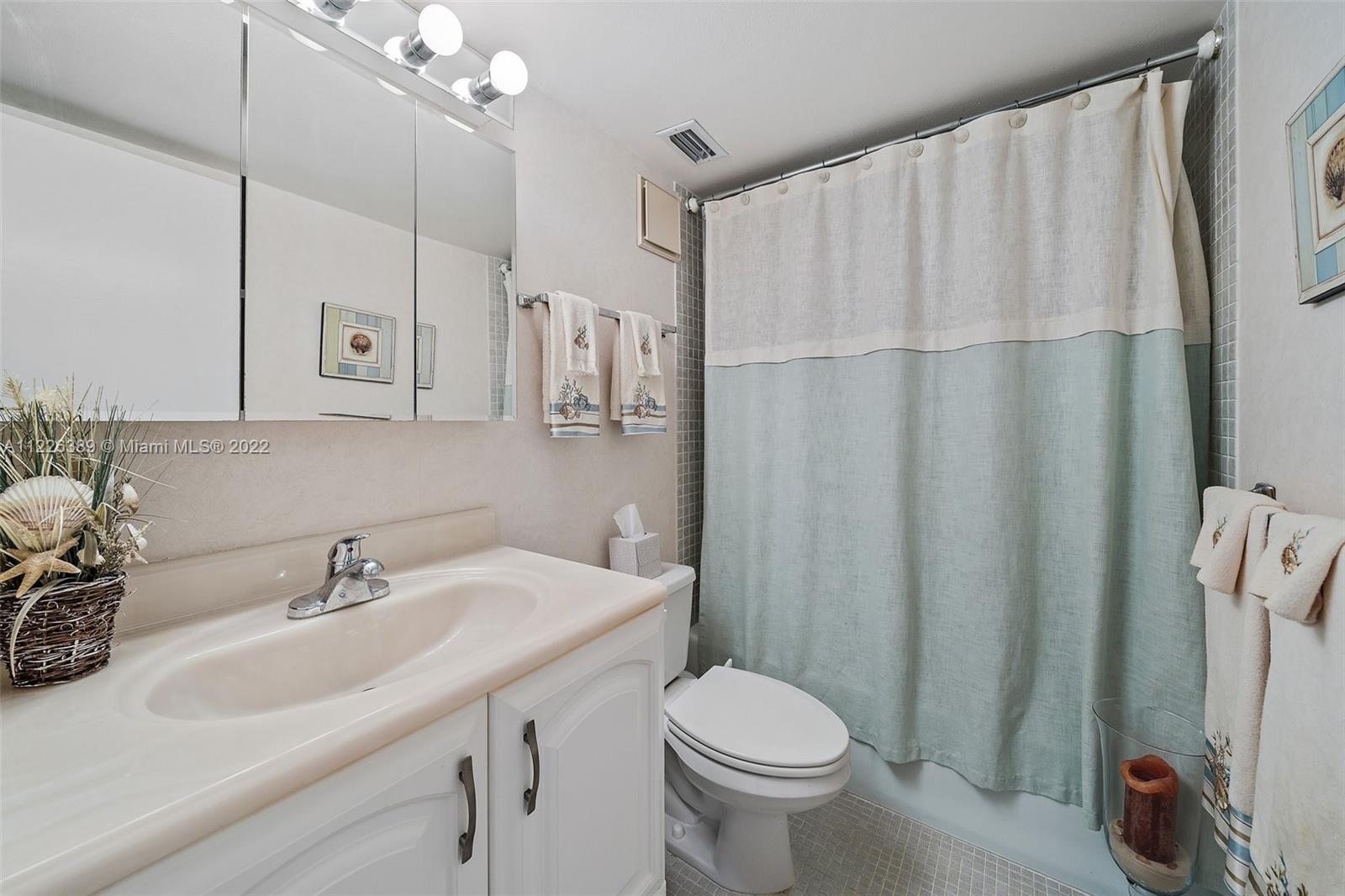 5335 Southeast Miles Grant Road, Unit 107 Stuart, FL 34997 - Photo 27 of 44 a bathroom with a sink a toilet and shower curtain